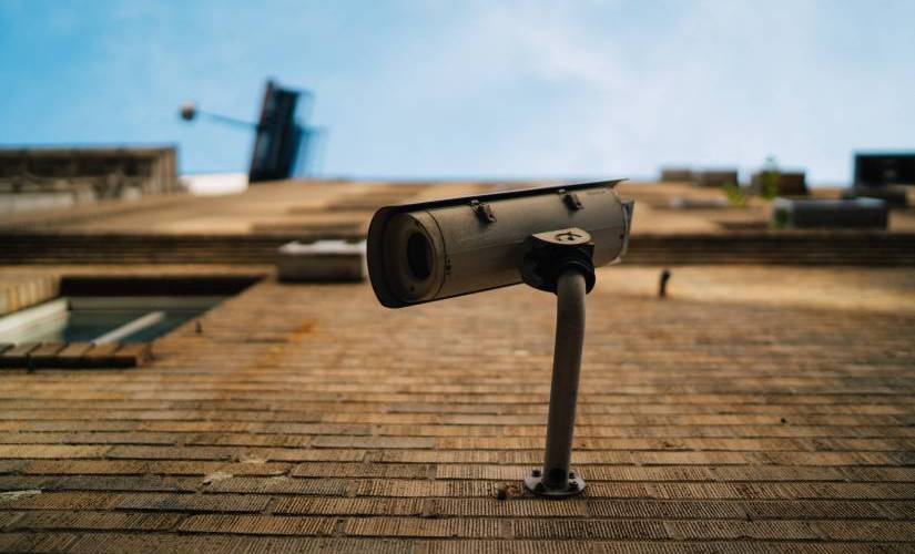 An outdoor security camera attached to a brown brick building.