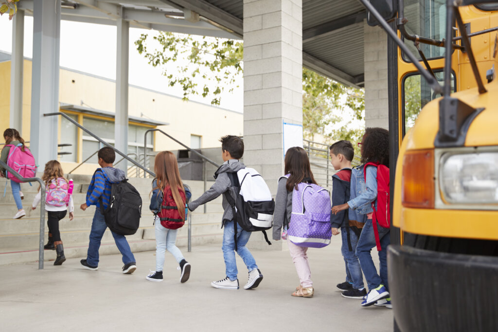 Image of children walking off of school bus and into a building.